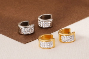 Close-up of gold and silver C-shaped hoop earrings with three rows of micro-pave crystals