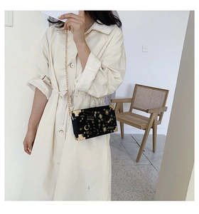 Close-up of black box bag featuring gold starry sky embroidery and metal corners