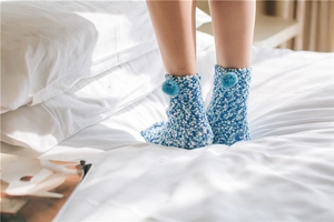 Close-up of thick coral fleece socks in blue and white with soft fuzzy pom-pom detail