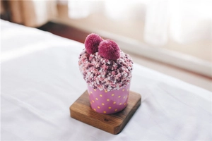 Close-up of fluffy coral fleece socks folded as a pink cupcake with purple pom-poms