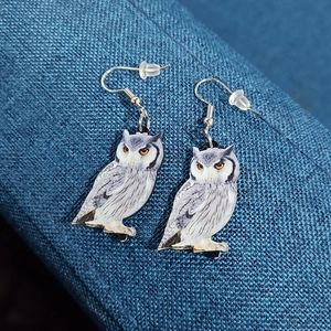 Detailed close-up of acrylic owl earrings with realistic print and silver hooks