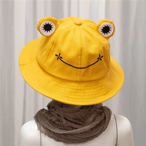 Detail of yellow cotton frog bucket hat with 3D eyes and embroidered smiley face