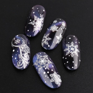 Detail of Christmas snowflake patterns on dark purple glitter gradient fake nails