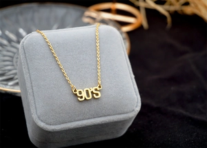 Macro shot of a gold 90'S letter pendant necklace displayed in a premium jewelry box
