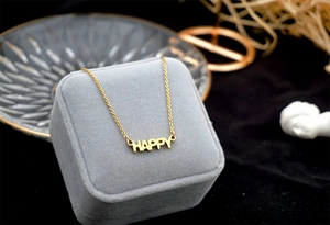 Macro detail of golden 'HAPPY' letter pendant on double-layer stainless steel necklace
