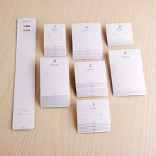 White paper jewelry display cards for earrings and necklaces on a wood background