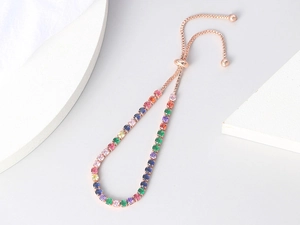 Detail of rose gold tennis bracelet with colorful round-cut cubic zirconia and slide clasp
