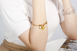 Detail of gold-plated stainless steel bangle with shell J letter and cartoon charms