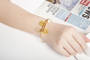 Detailed shot of a gold charm bracelet with boy-girl pendant and white pearls