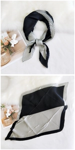Close-up of pleated silk scarf with black and silver grey geometric color block patterns