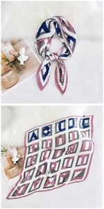 Detailed view of pleated silk scarf with geometric letter patterns and royal blue accents