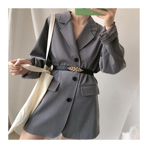 Close-up of a women's skinny black belt with a gold leaf buckle on a grey blazer