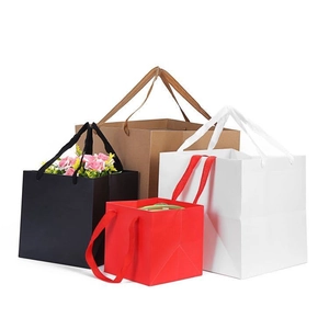 Vue détaillée de sacs cadeaux carrés en papier avec anses en tissu en noir, blanc et marron