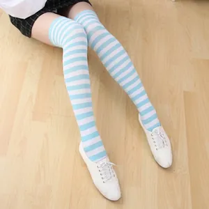 Close-up of blue and white striped knee high socks with white sneakers on wooden floor
