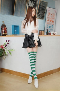 Detailed knit texture of green and white striped over-knee high socks on a model