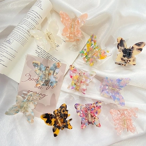 Flat lay of colorful butterfly acetate hair claws on elegant white silk and paper