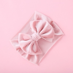 Macro view of velvet bow and ribbed elastic fabric on a pink baby headband