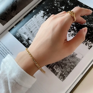 Detail of 925 silver gold braided bracelet and chain ring worn with magazine background