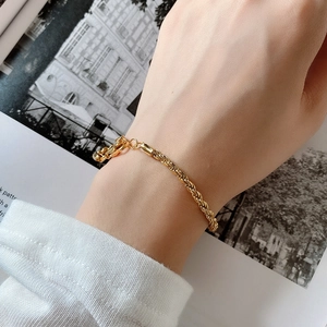 Detailed view of a gold minimalist rope chain bracelet worn on a woman's wrist