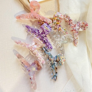 Flat lay of colorful acetate hair clips with glitter and gold foil accents on wooden tray