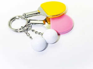 Close-up of mini pink and yellow table tennis racket keychains with white ping pong balls