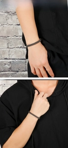 Close-up of men's black stainless steel wheat link bracelet with industrial texture