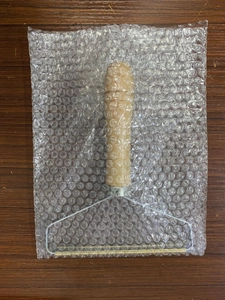 Detailed shot of a wood-handle manual lint remover wrapped in protective bubble packaging