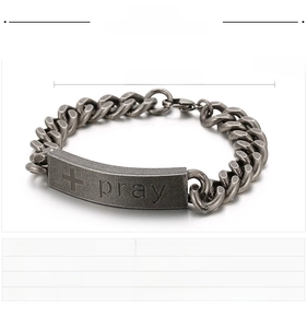Detailed macro view of vintage stainless steel bracelet with engraved cross and pray text
