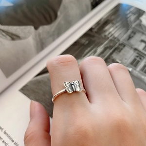 Close-up of vintage silver butterfly ring on hand against fashion magazine background