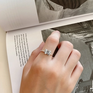 Detailed close-up of a silver butterfly ring with black etched texture on a model hand