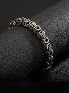 Macro detail of vintage punk stainless steel king chain bracelet on textured surface
