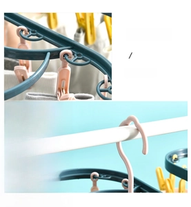 Detail of windproof groove and removable pink clips on a green plastic laundry hanger