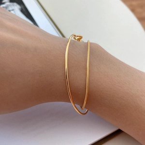 Minimalist double layer open gold bangle with snake chain texture on white background