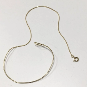 Detailed view of a slender gold snake chain bracelet with a spring clasp closure