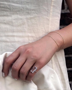 Close-up of minimalist 925 sterling silver bangle and emerald-cut gemstone ring on hand