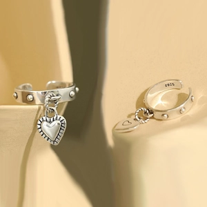 Detailed shot of S925 sterling silver open ring featuring heart charm and rivet texture
