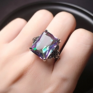 Macro shot of rectangular rainbow topaz ring with vintage engraved silver band on hand