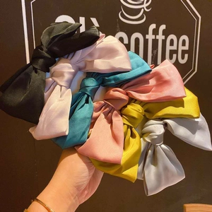 Close-up of assorted colorful satin bow hair clips showing premium silky texture and volume