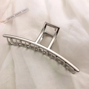 Macro view of silver geometric metal hair claw clip with polished finish and large comb teeth
