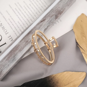 Detailed close-up of golden hollow metal hair claw clip on a professional grey background