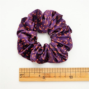 Halloween purple velvet scrunchie with orange pumpkin patterns and scale reference