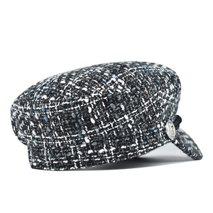 Detail shot of tweed newsboy cap texture with silver metal button and braided cord