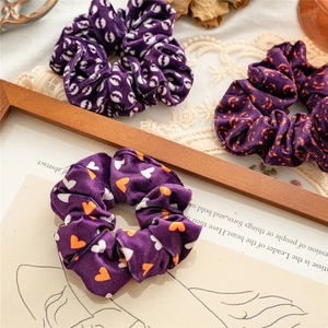 Detailed view of three purple velvet scrunchies with heart and moon patterns on lace fabric