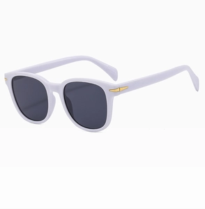 Dettaglio occhiali da sole in acetato bianco con inserti metallici a freccia dorata