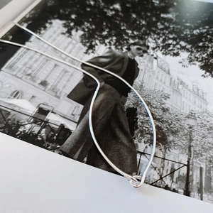 Silver herringbone chain necklace displayed on a modern black and white fashion magazine