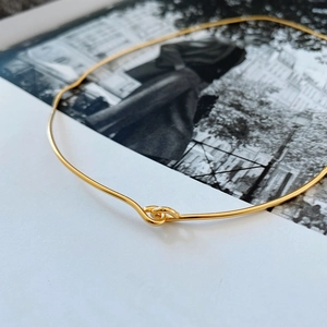 Macro detail of polished gold interlocking double ring links on a sleek metal choker