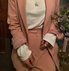 Detailed shot of an irregular silver wide ring paired with a peach pink blazer suit