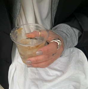 Close-up of a silver irregular pleated ring and a minimalist gold band worn on a hand