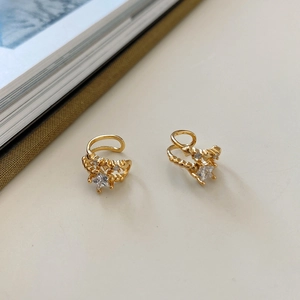 Detail of gold star ear cuff with sparkling zircon stones on a clean minimal background