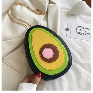 Detailed view of avocado-shaped PU leather crossbody bag with golden chain strap on white blazer